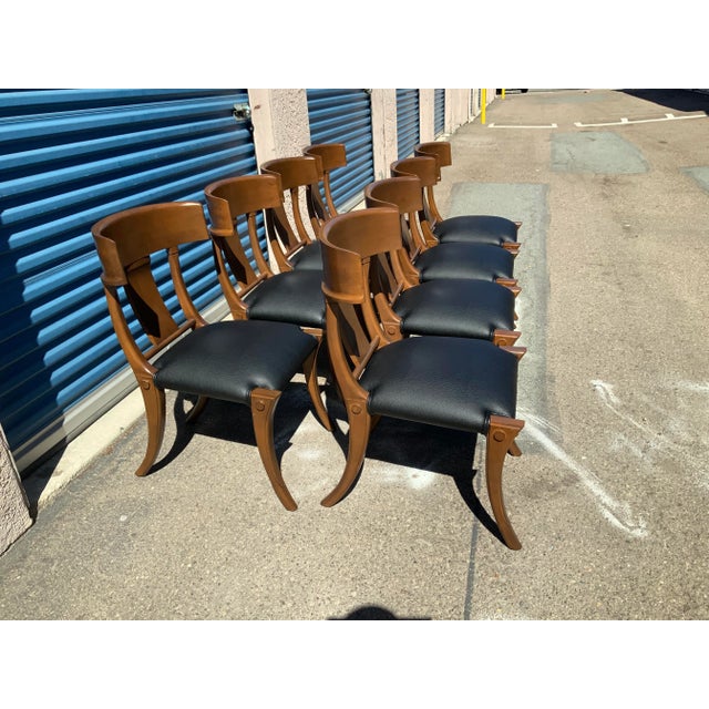 Klismos style dining chairs. The chairs are made of solid alder with a walnut finish and upholstered is a black faux...