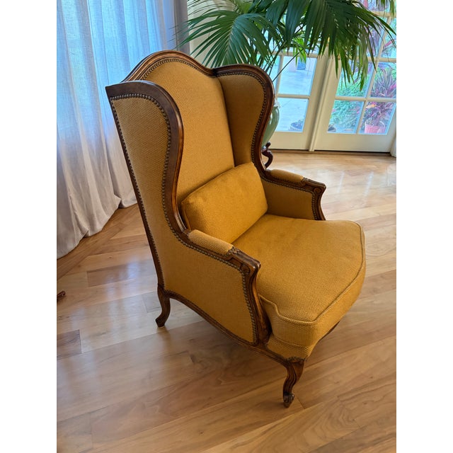 Comfortable Old English-style Wing Backed Arm Chair. Mustard gold fabric with wood frame supports.