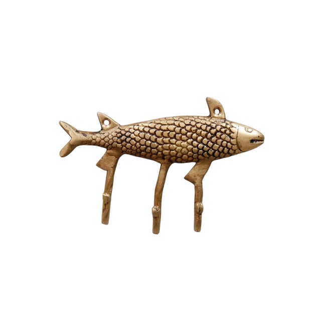 A brass fish wall fixture with three hooks. A central bar is cast in the oval shape of a fish, complete with fins....