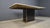 Large dining table with a white marble top, a brass frame and a brass and black glass base. The combination of these...