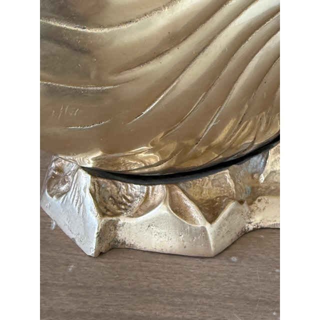 A striking Vintage Brass Nautilus Shell Planter or Wine Cooler with a sculptural seashell design perched on a textured...