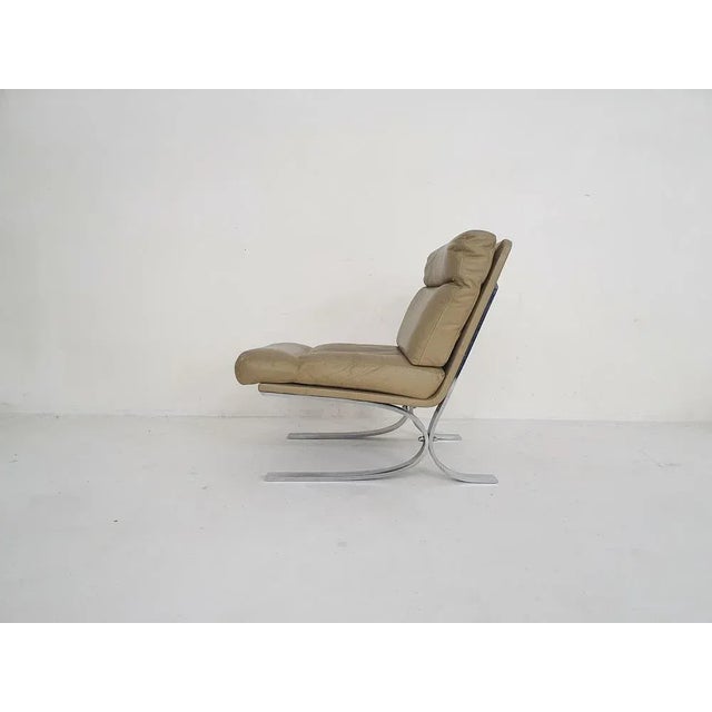 High quality chromed metal lounge chair with an off-white / beige leather upholstery. We think they are designed by Paul...