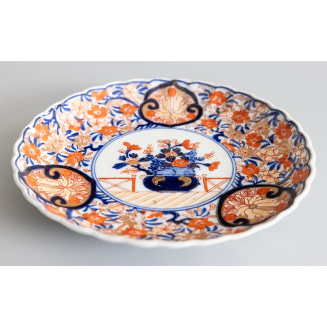 A striking 19th century antique Imari plate with a scalloped edge. Featuring vibrant oranges, blues, and green. The multi-...