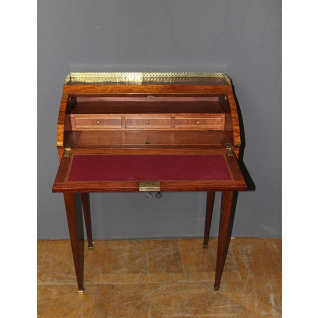 A small Louis XVI style roll-top desk in marquetry of native woods forming cubes. It opens with a cylinder that reveals...