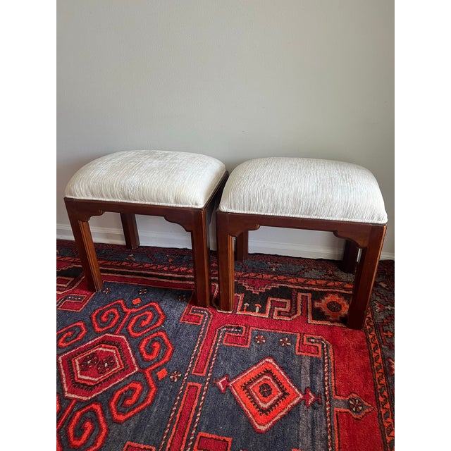 A handsome pair of vintage Ethan Allen stools featuring warm mahogany-toned wood frames, subtly flared legs, and Asian-...