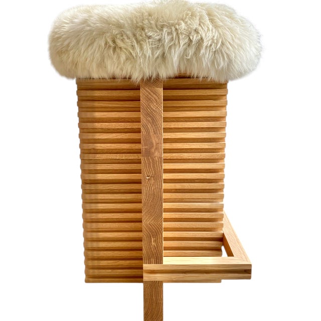 Architectural slatted white oak base with foot rest and a New Zealand sheepskin covered seat. Designed and built by Bertu.