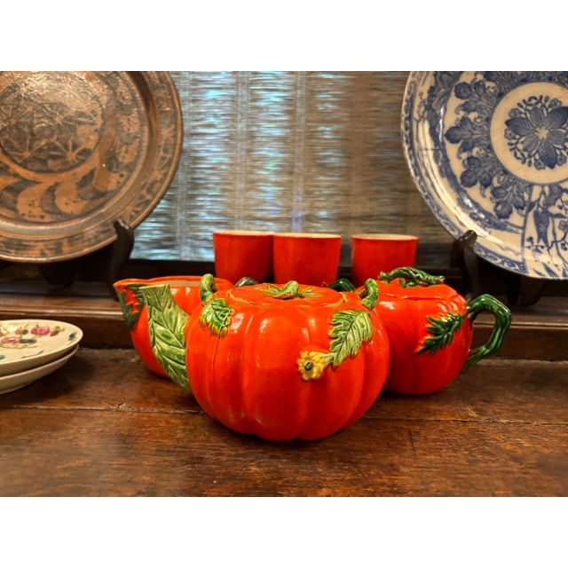 A playful tea set comprised of one teapot, one sugar pot, one creamer jug, and three small cups; each piece resembles an...