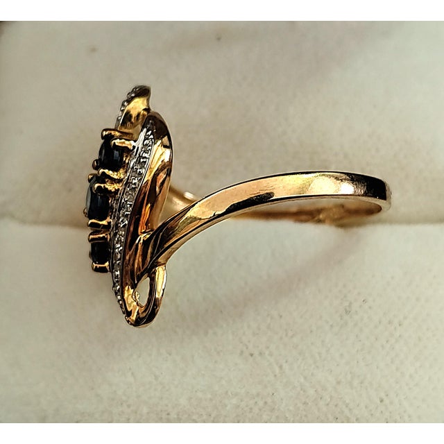 This very pretty 18K (750/1000) gold band ring features three deep blue sapphires flanked by two sparkling bands....