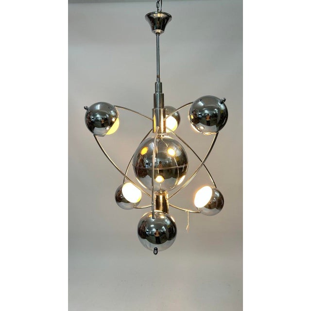 Chromed metal chandelier featuring a spherical structure. It consists of a large central sphere surrounded by six smaller...