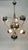 Chromed metal chandelier featuring a spherical structure. It consists of a large central sphere surrounded by six smaller...