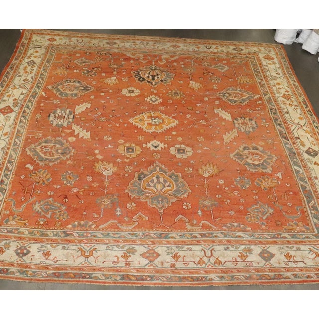A large late 19th Century Antique Oushak rug featuring a large scale all over design floating on a pumpkin orange field...