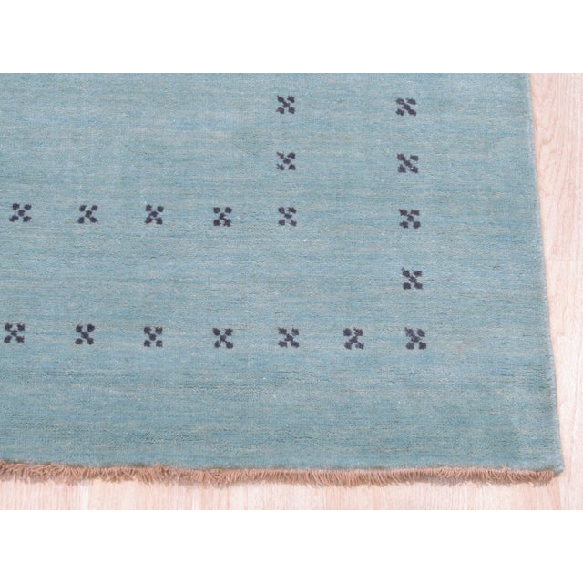 A 10' x 14' hand-knotted wool rug with a plain aqua Gabbeh-style field with a simple dotted border in a deeper blue. Newly...