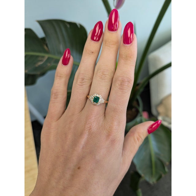 A Colombian emerald glows in vivid, slightly bluish green at the centre of this solid 14K yellow gold ring, framed by...