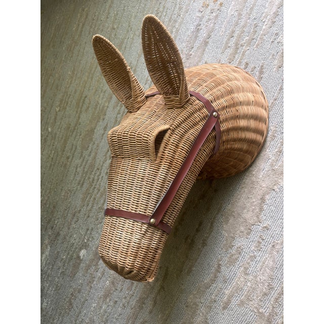 A large woven wicker horse head with a brown vinyl harness with perky ears and raised eyebrows and a little woven bow...