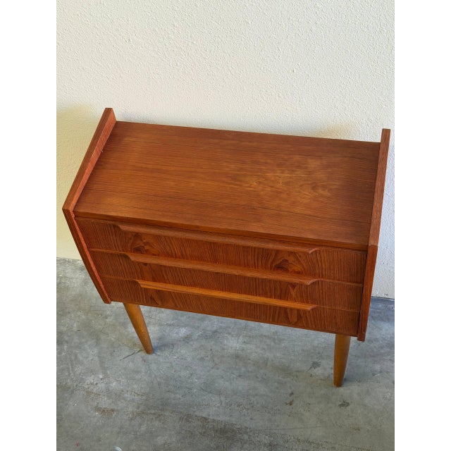 Charming Mid Century Modern Danish chest crafted in warm teak, featuring clean architectural lines, sculpted drawer pulls,...
