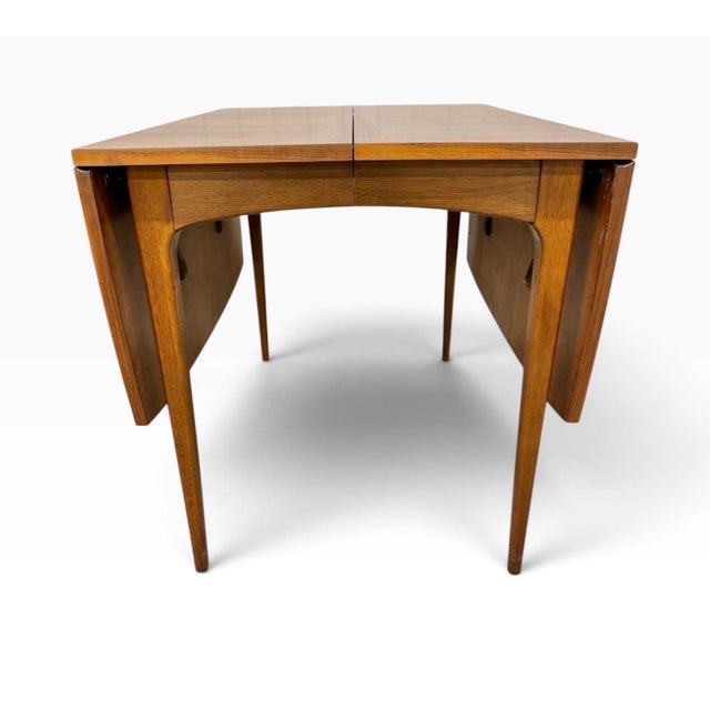 A beautifully designed Mid-Century Modern Lane “Rhythm” Drop-Leaf Walnut Dining Table, circa 1960s. Crafted in richly...