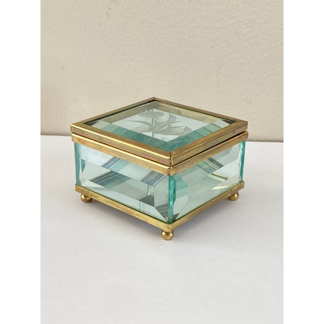 Superb rectangular jewelry box in clear glass with a gilt brass mount, resting on four small ball feet. Hinged glass lid...