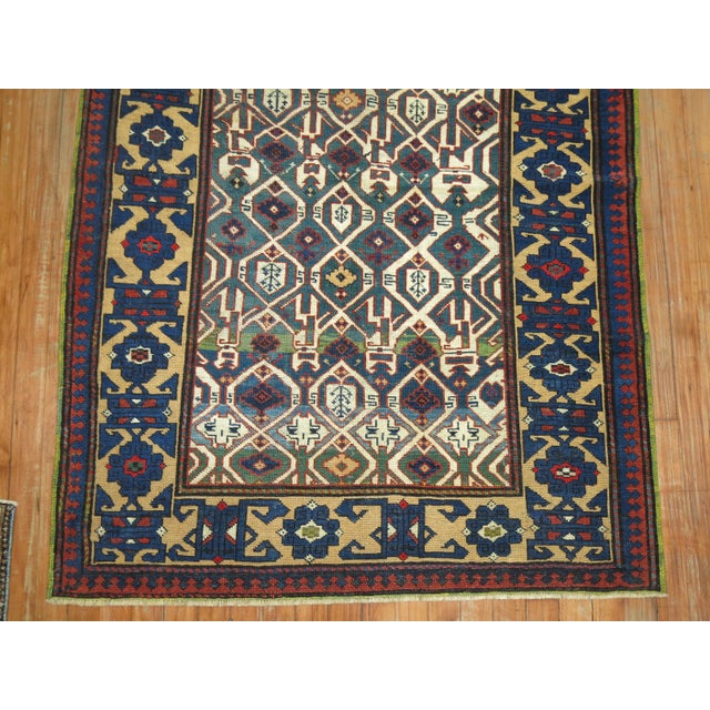An early 20th century Caucasian Kuba rug with a geometric design in green and blue Measures: 3'7" x 6'1" This captivating...