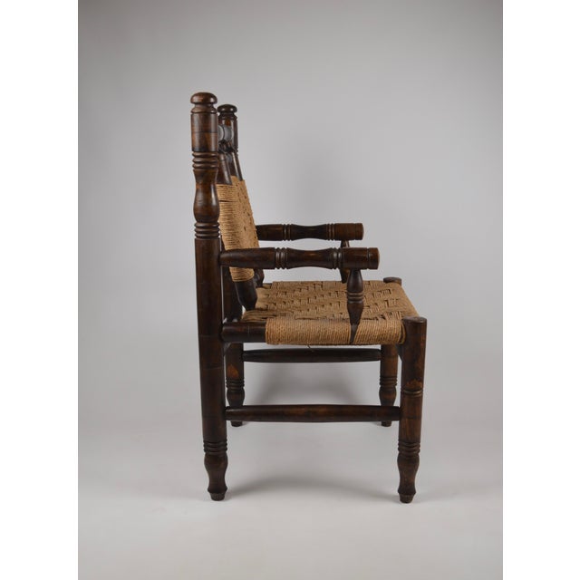 French armchair from the 1940s–1950s, crafted in solid wood with a rich, dark patina and traditional turned details. The...