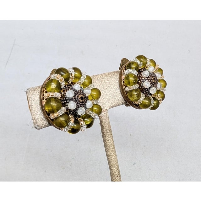 1960s round goldtone olive green beads with white and clear accent beads clip earrings. Marked "ORNELLA MADE ITALY" on the...