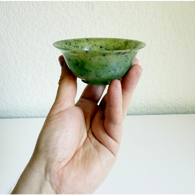 An intriguing Chinese spinach jade bowl, a classic piece of carved lapidary art crafted from translucent green nephrite...