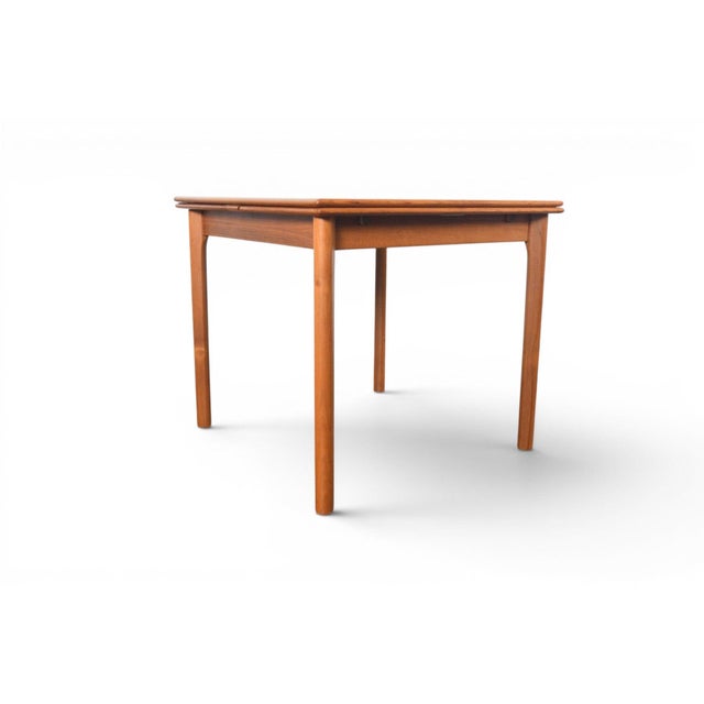 A compact square table that opens to seat six with a smooth, effortless draw leaf mechanism. Clean tapered legs, warm teak...