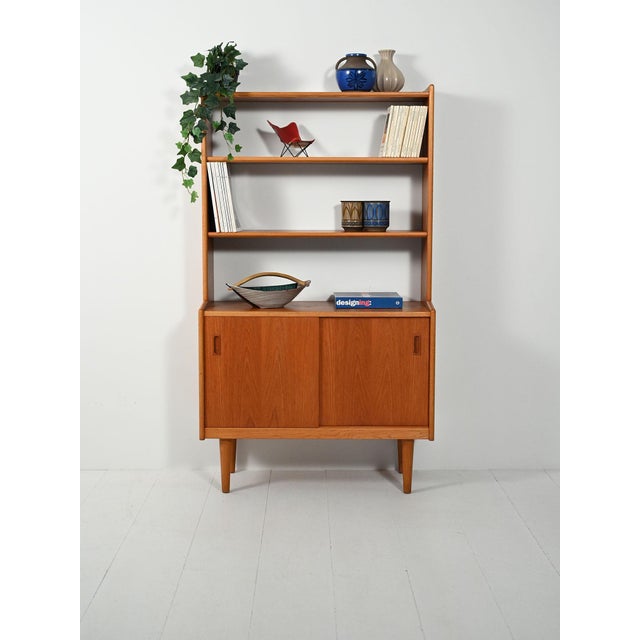 1960s teak bookcase with adjustable exposed shelves, a lower compartment with sliding doors and recessed handles, turned...