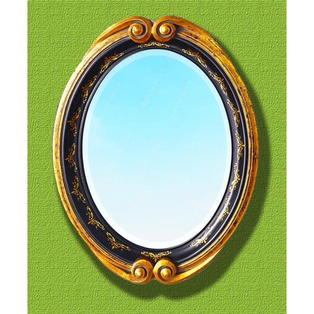 An ornate, gold and black oval Contemporary beveled mirror by the exclusive John Richard furniture company. The deeply...
