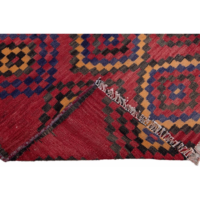 Beautiful kilim handmade wool runner with a red field. This Vintage flatweave rug features a gorgeous all-over geometric...