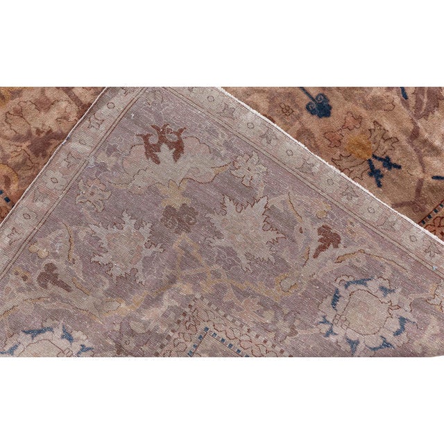 An early 20th century antique Indian area rug, the cream field with an allover trellis of palmettes, split leaves, and...