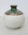 Globular form with creamy white body glaze. The mouth and shoulders are covered in two color glazes mixing and flowing...
