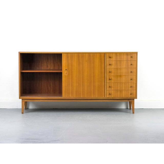 Stunning walnut sideboard with two sliding doors featuring oval recessed handles and six drawers with delicate, teardrop-...