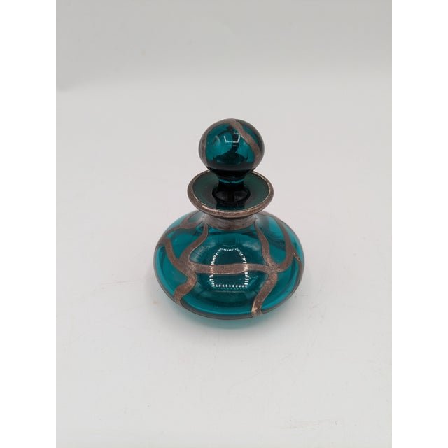 Art Nouveau Sterling Silver–Overlay Green Glass Bottle with Stopper Dimensions: 2″ H × 7″ circumference Materials:...