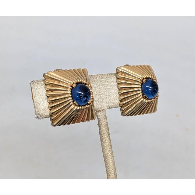 Late 1940s square goldtone ribbed raised center with cabochon faux-sapphire in the middle clip earrings. Marked "MAZER" on...