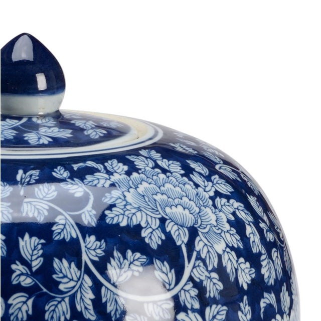 Hand painted blue ceramic with a removable lid and decorated with a white flower pattern.