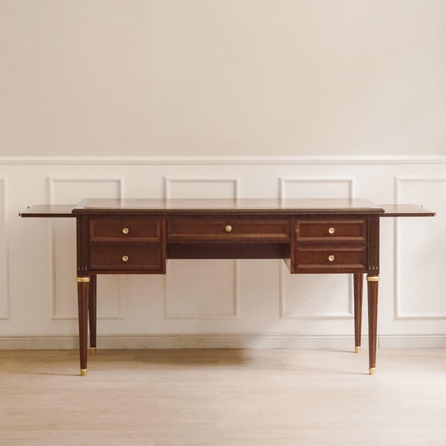 A Louis XVI-style desk, likely made around the mid-20th century, with a leather-covered writing surface and pull-out...