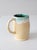 This vintage handmade ceramic mug features a cream glaze that transitions to turquoise green along the rim and interior,...
