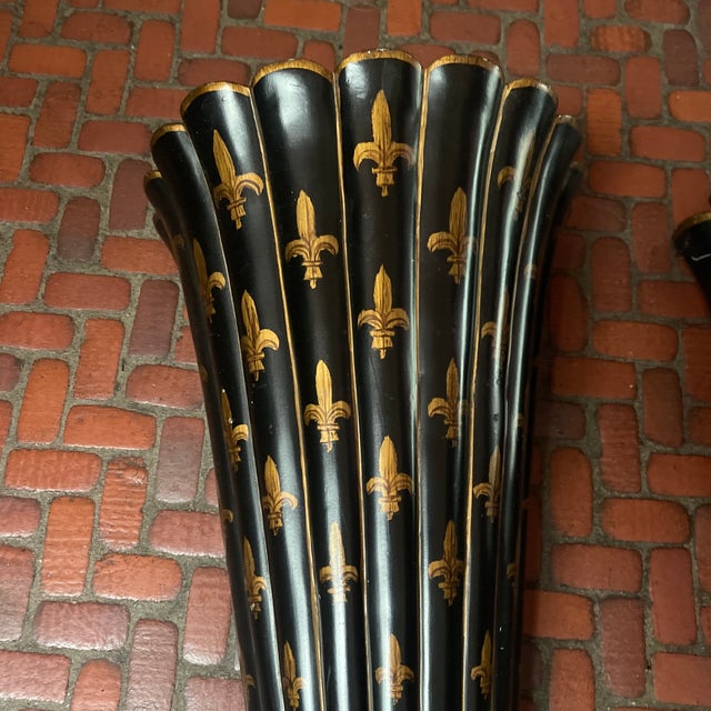 A pair of black wooden wall planters with removable metal planters and with gold fluer de lis motifs painted on the...