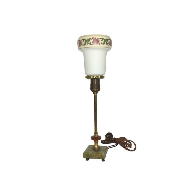 This antique table lamp features a green onyx base, brass stem, and floral glass shade with Bakelite accents, blending...