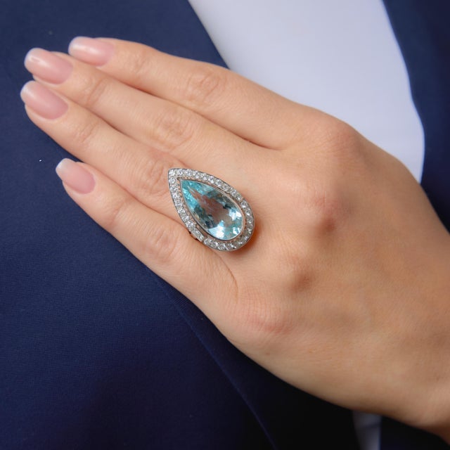 This striking Art Deco inspired cocktail ring centers on a breathtaking 10.17 carat Portuguese cut pear shape aquamarine,...
