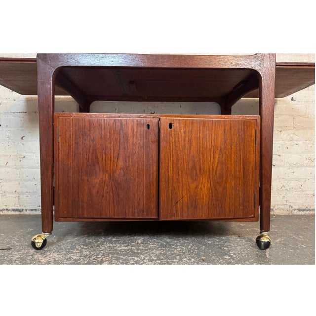 Danish Modern bar cart by Falster Møbelfabrik. Crafted in rich teak with extendable Formica top. Features ample adjustable...