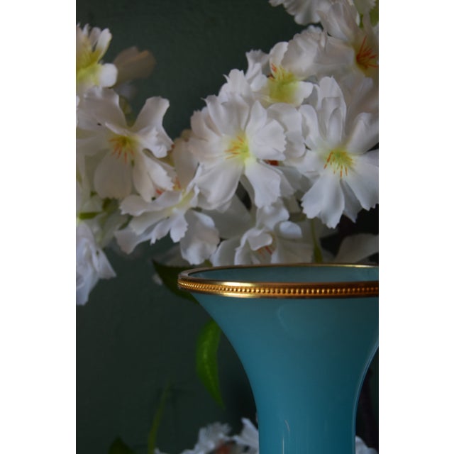 A striking French opaline vase in a rich turquoise blue, finished with a finely detailed gilt bronze rim. The elegant form...