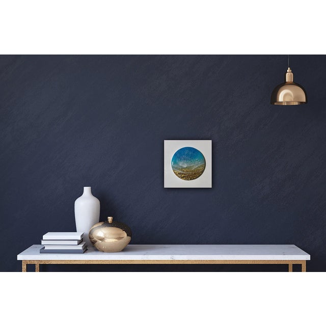 This circular mixed media piece on ceramic captures the dynamic interplay of ocean waves meeting a sandy shore. The...