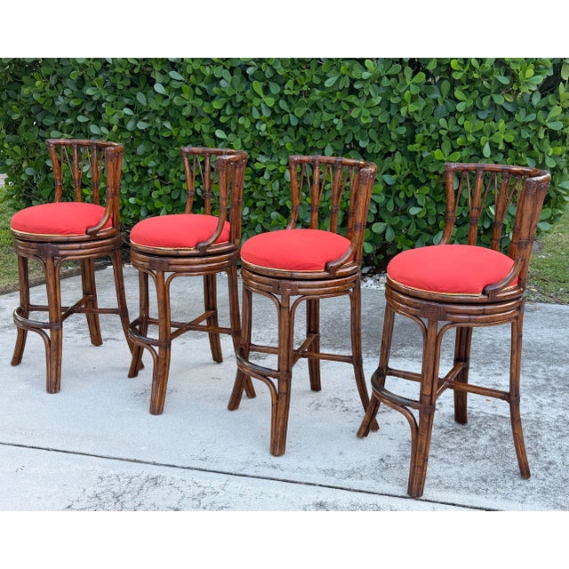 A set of four Tommy Bahama Island Estate faux-bamboo swivel barstools featuring sculptural frames in a rich plantation...