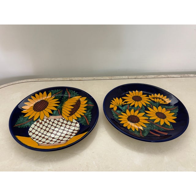 Vintage pair of Mexican earthenware wall plates with sunflower motif. Brightly painted in indigo, brown, and goldenrod....