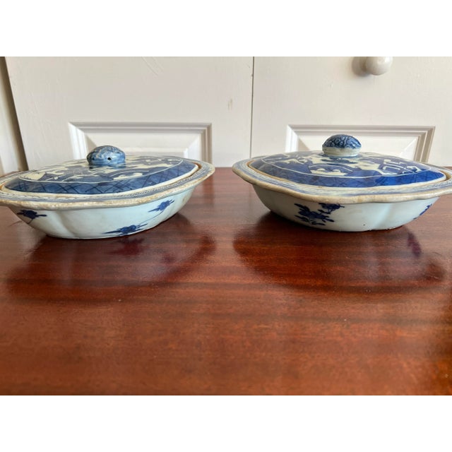 A pair of chinese export style canton blue and white covered dishes. Melon finials with landscape decoration to each