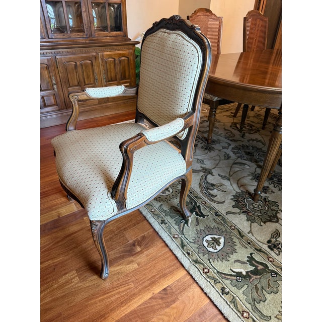 Beautiful, upholstered vintage Louis XV armchair with intricate motifs and open arms.