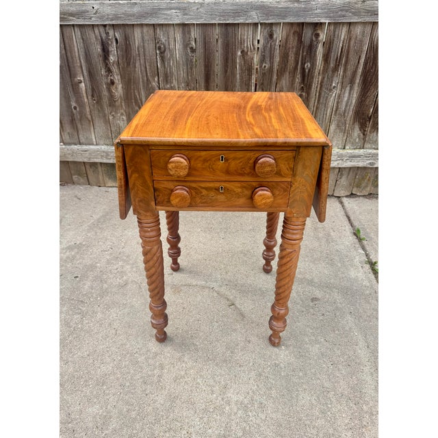 A beautifully proportioned antique American drop-leaf work table, dating to approximately 1840–1860. The top is solid...