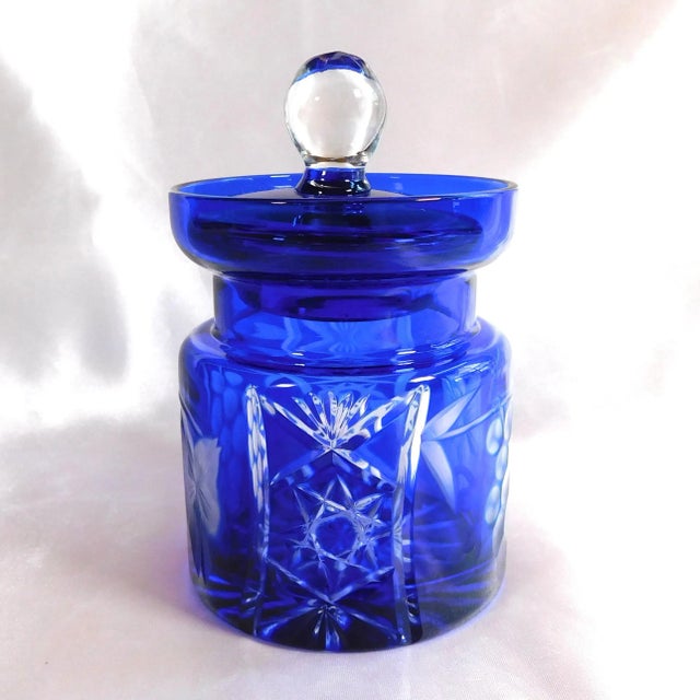 This is a blue glass, cut to clear, jelly jar, honey pot or sugar bowl with a spoon cut out in the lid. I cannot find a...