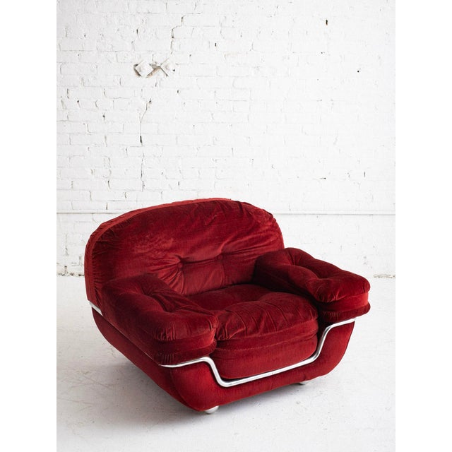 Space age Italian armchair upholstered in red velvet corduroy with tubular chrome accent wrapping around the frame....